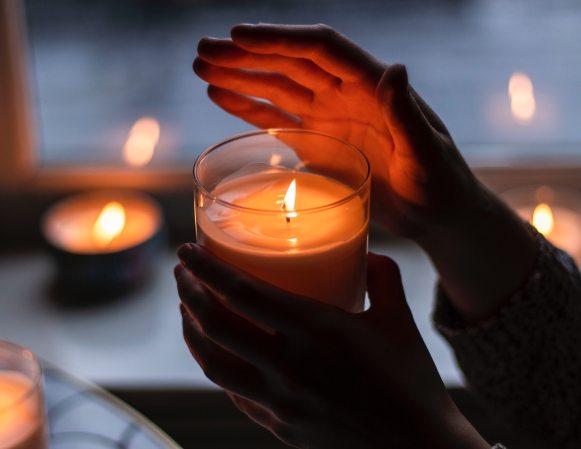 A person holding a lit candle in a dark room