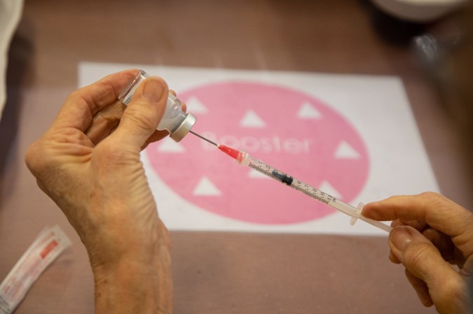 Close-up at the syringe, vial and hands of a woman preparing the Moderna COVID booster shot