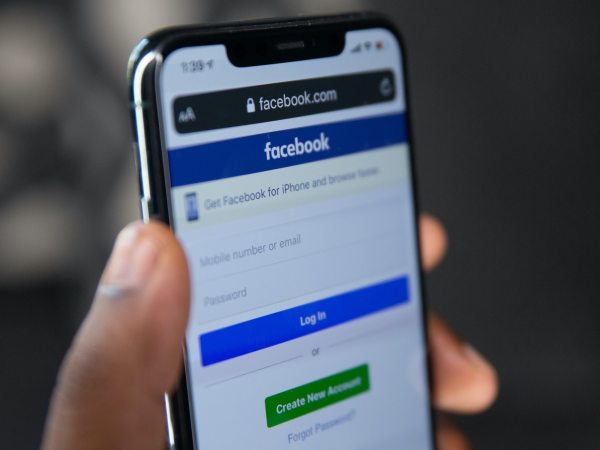 Close-up of hand holding smartphone displaying Facebook login screen