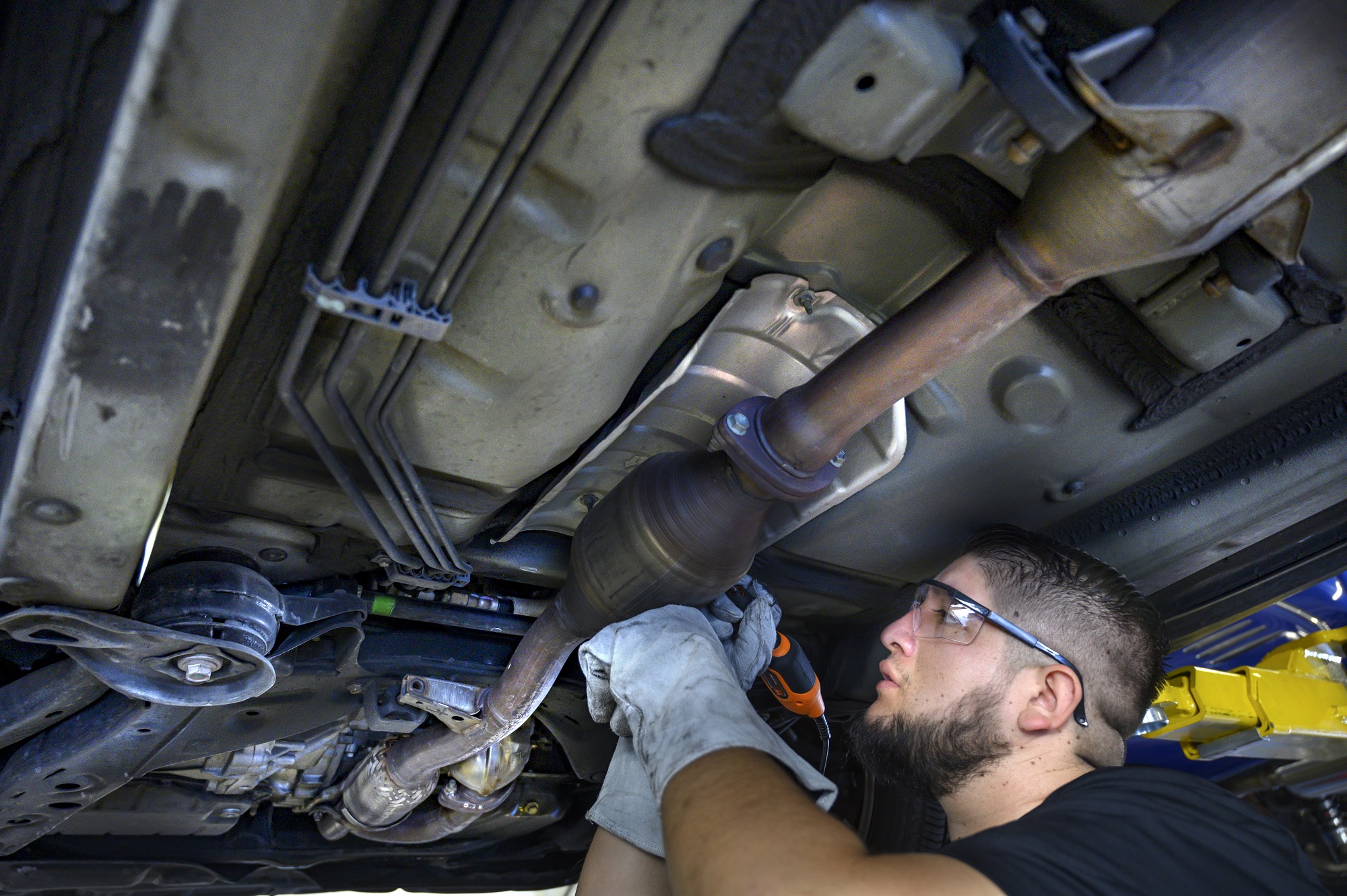 Auto tech etching numbers into catalytic converter under car to prevent theft