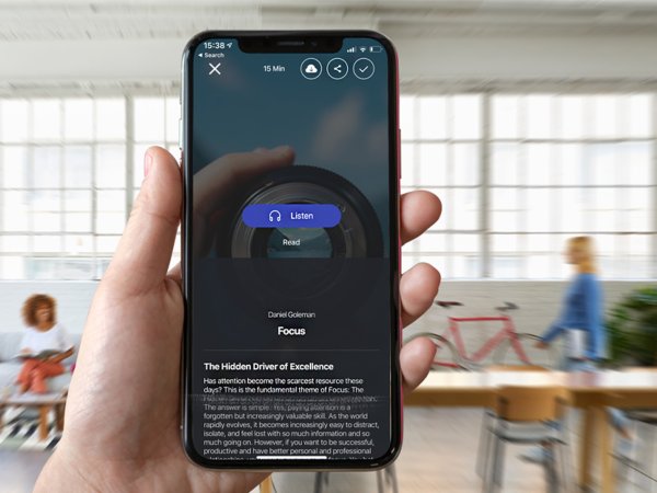 A person in a coworking space using their phone to listen to a micro book