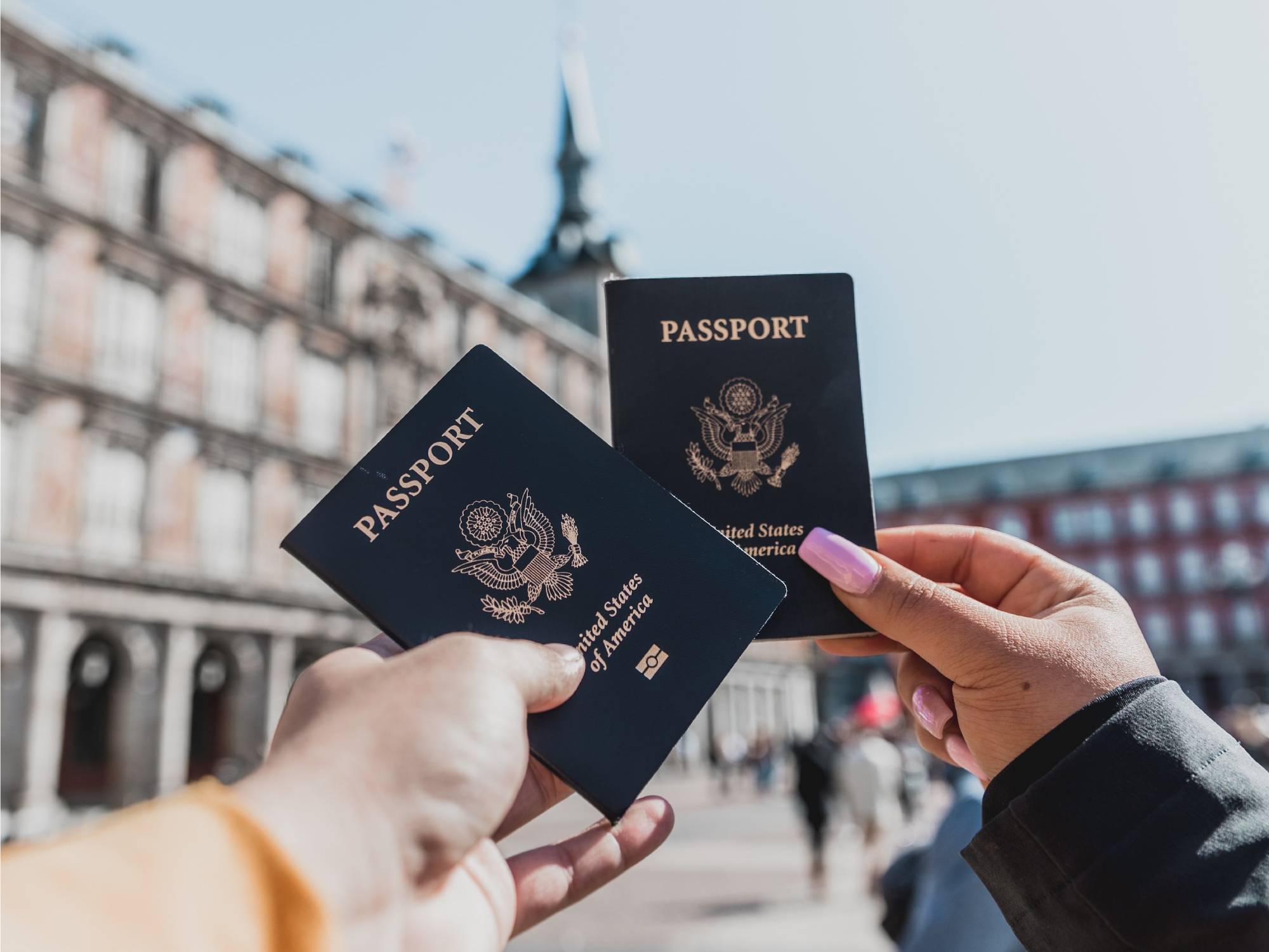 two hands holding us passports in a plaza in madrid spain