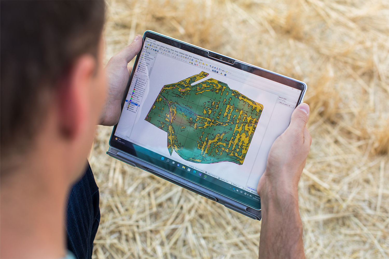 A man holds a tablet showing a multispectral image of a field.