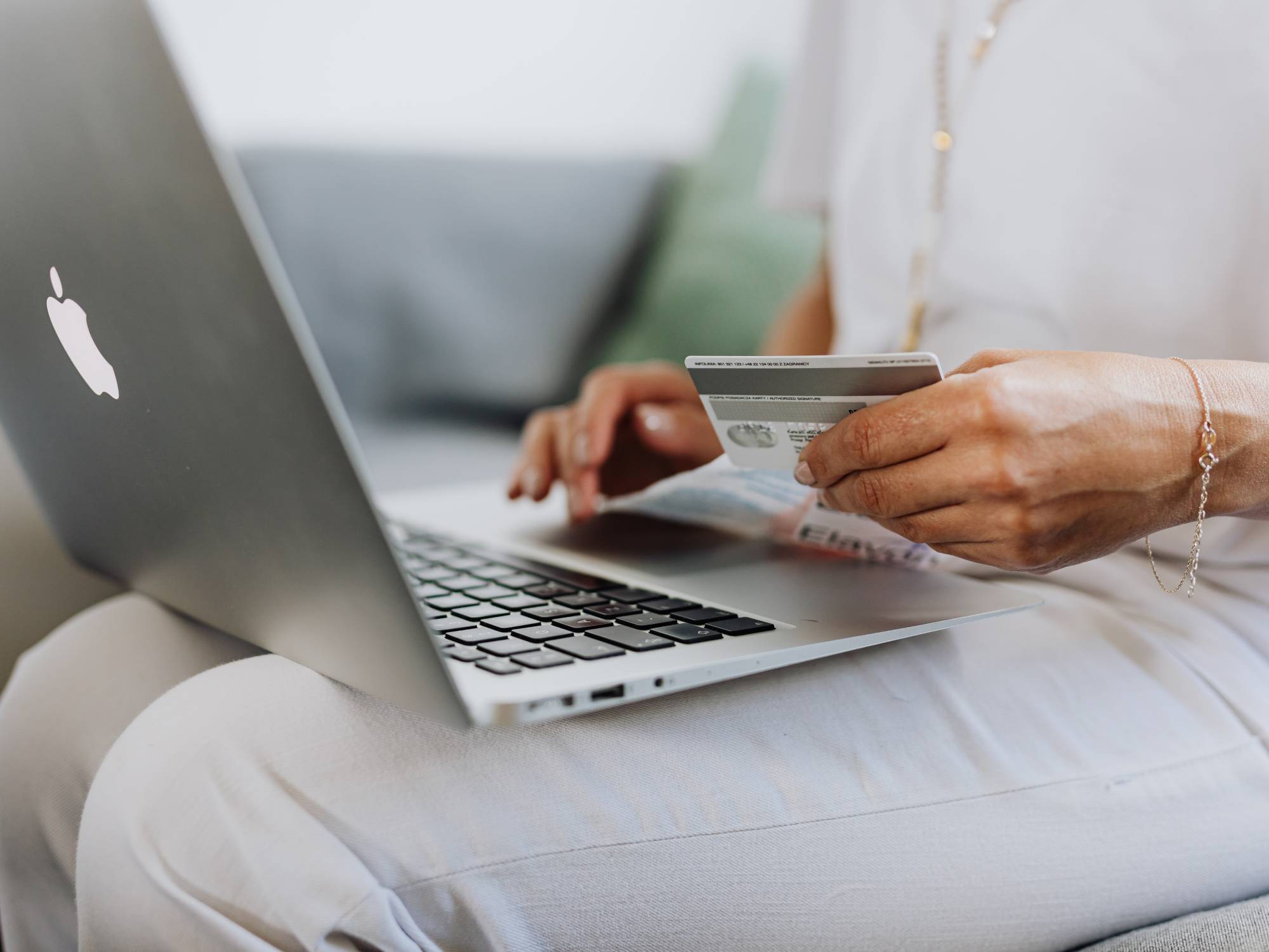 person with laptop on their lap and credit card in hand