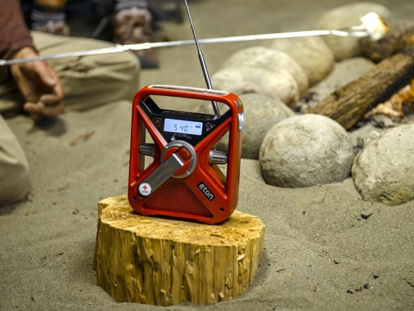 An American Red Cross radio sits on a log near a campfire