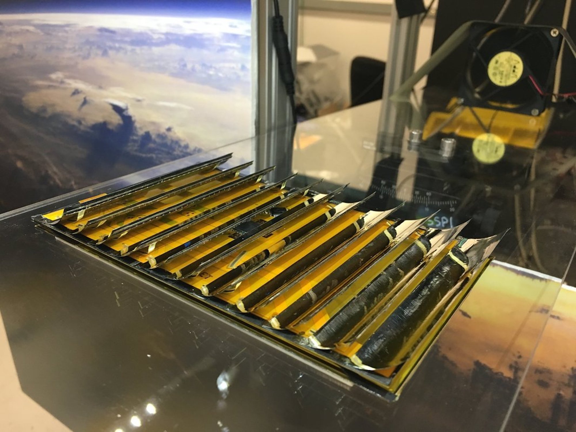 Caltech solar power satellite prototype on space station table with earth horizon in window background