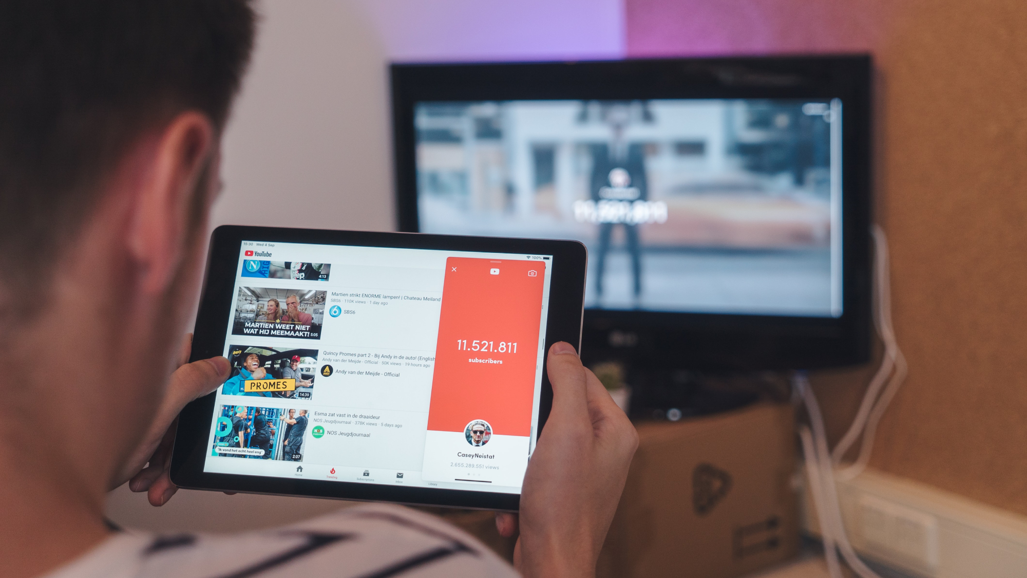 A man watching YouTube on a tablet while sitting in front of a desktop computer.