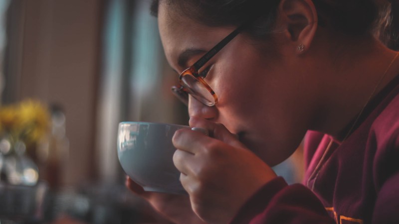 A woman sipping from a teacup while taking a break.