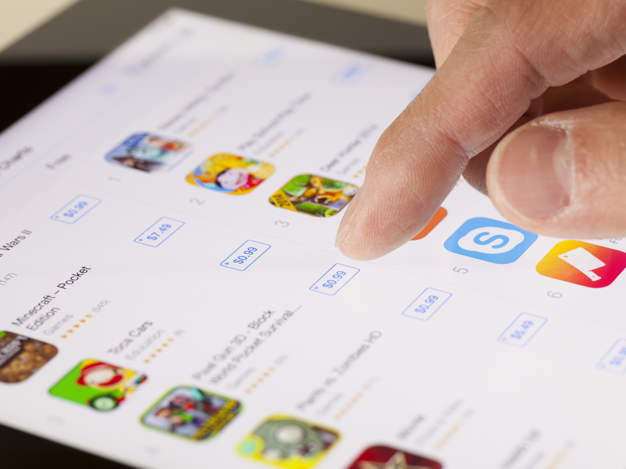 close-up of hand browsing iPad App Store screen with download options