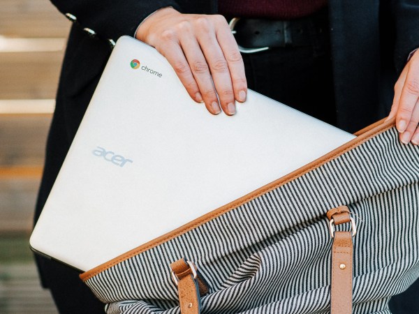 Person putting chromebook inside messenger bag