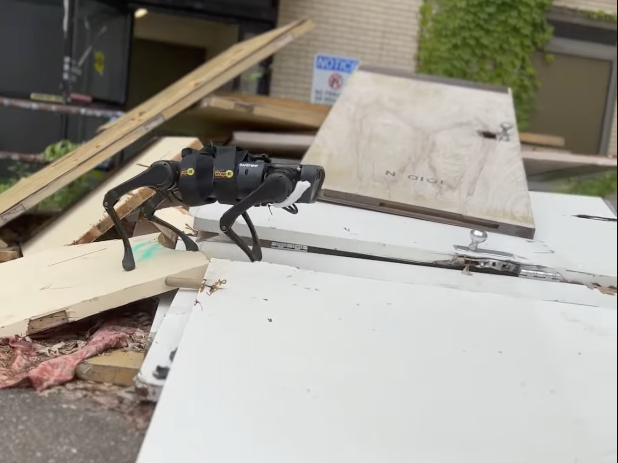 Four-legged robot walking across pile of boards and building materials during mobility test