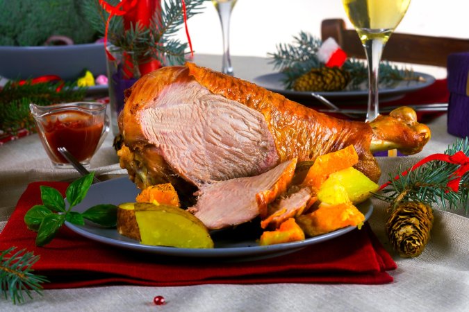 a cooked turkey drumstick on a plate that's sliced revealing its dark pink meat