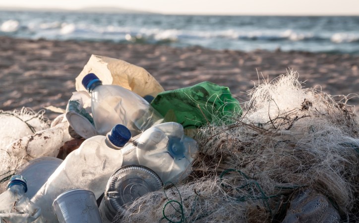 Plastic bottles and fishing nets and other trash on sea beach