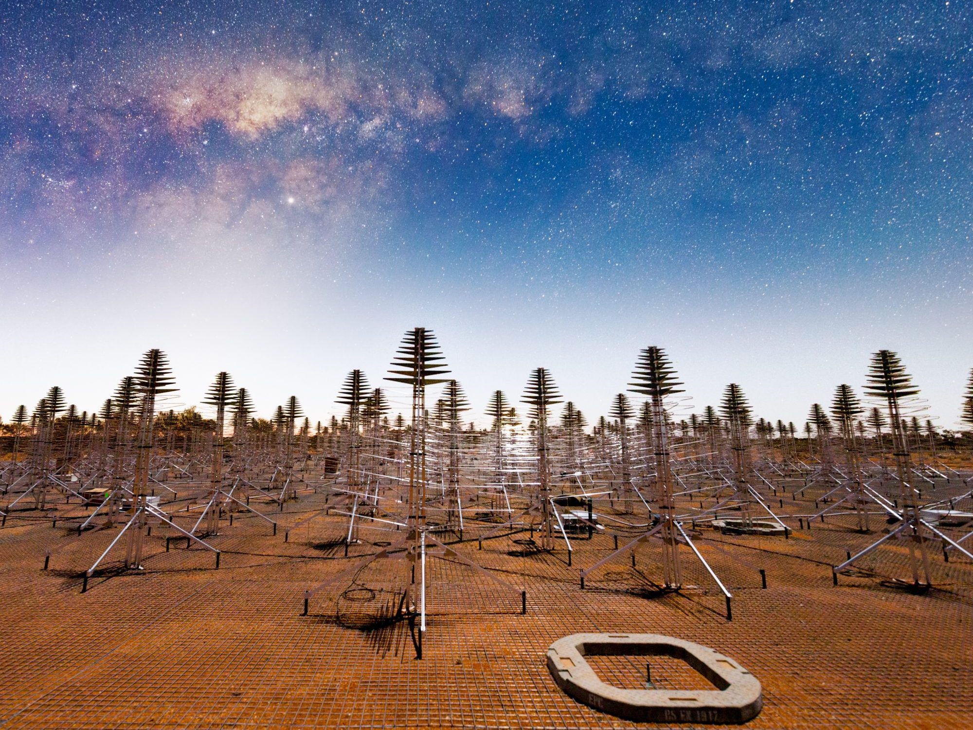Array of Australian radio telescope prototypes built in the Outback against a sky showing stars and the Milky Way galaxy