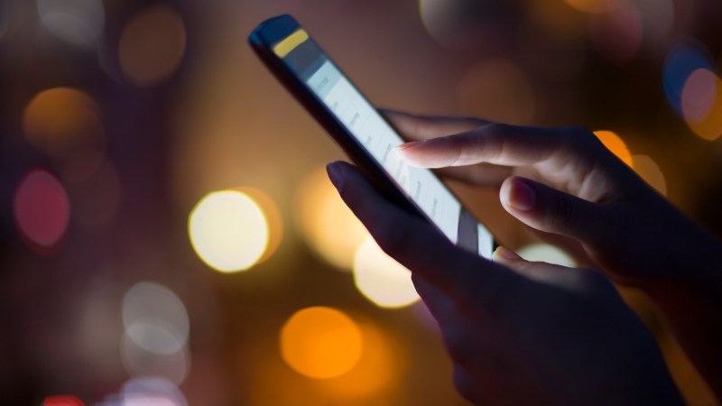 Woman using her mobile phone , city skyline night light background