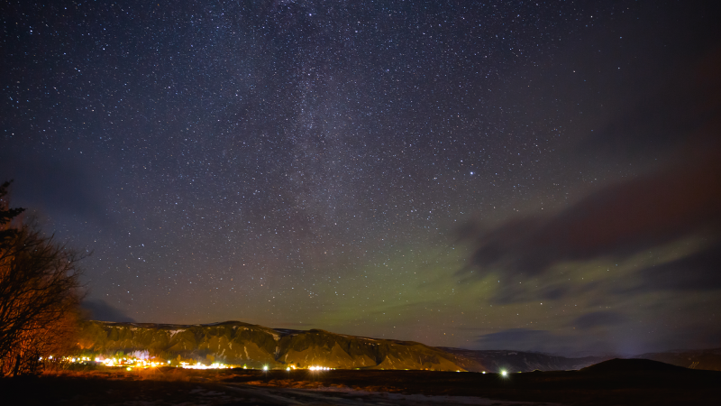 A starry night sky over a populated area with lights.