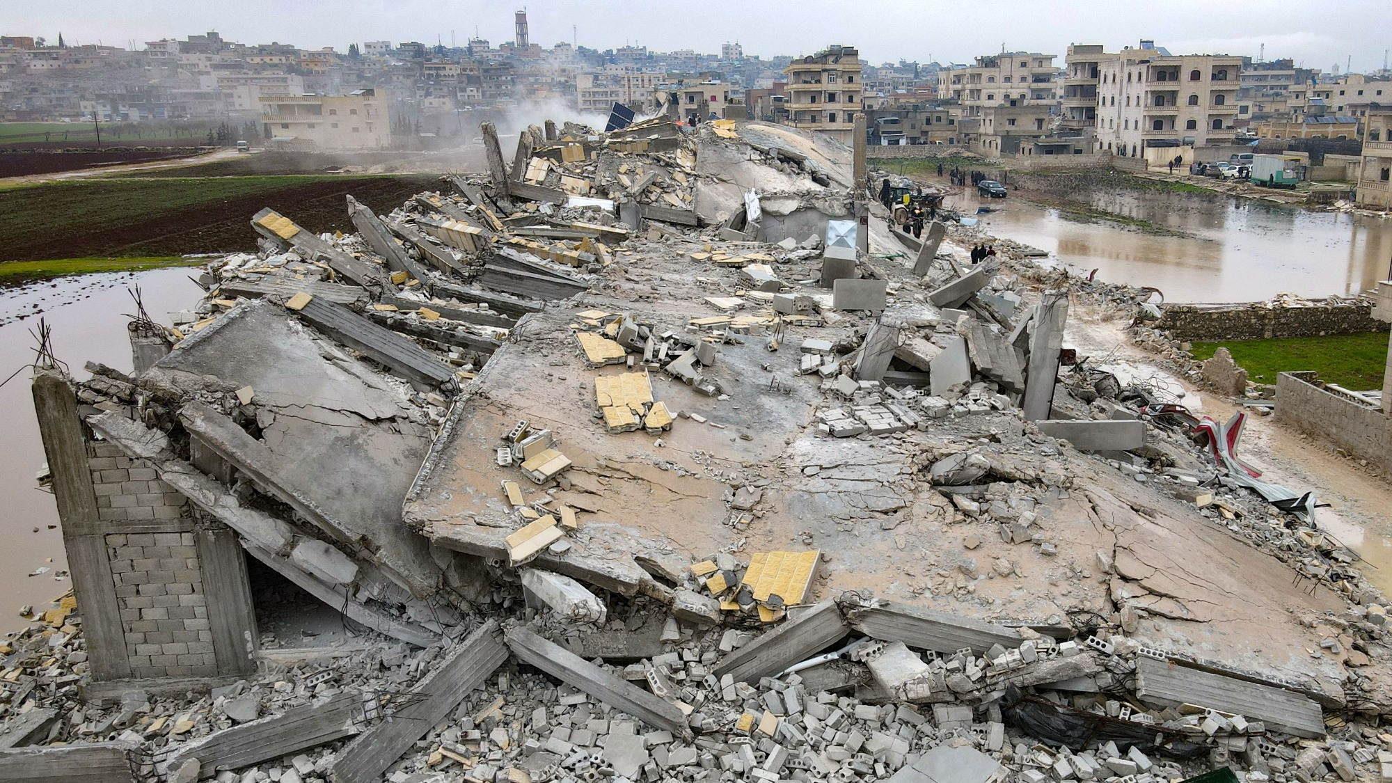 This aerial view shows residents helped by bulldozers, searching for victims and survivors in the rubble of collapsed buildings, following an earthquake in the town of Sarmada in the countryside of the northwestern Syrian Idlib province, early on February 6, 2023.