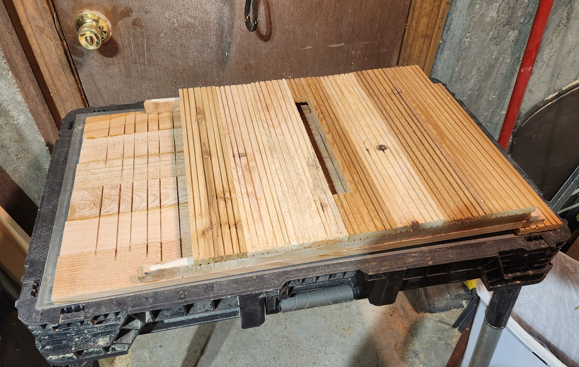 The interior of a partially assembled DIY bat house, showing the grooved back panel, the rails that leave an opening for the bats, and the middle panel on top of the rails.