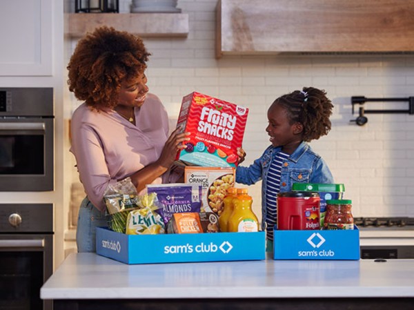 People looking at their grocery store haul in their kitchen.