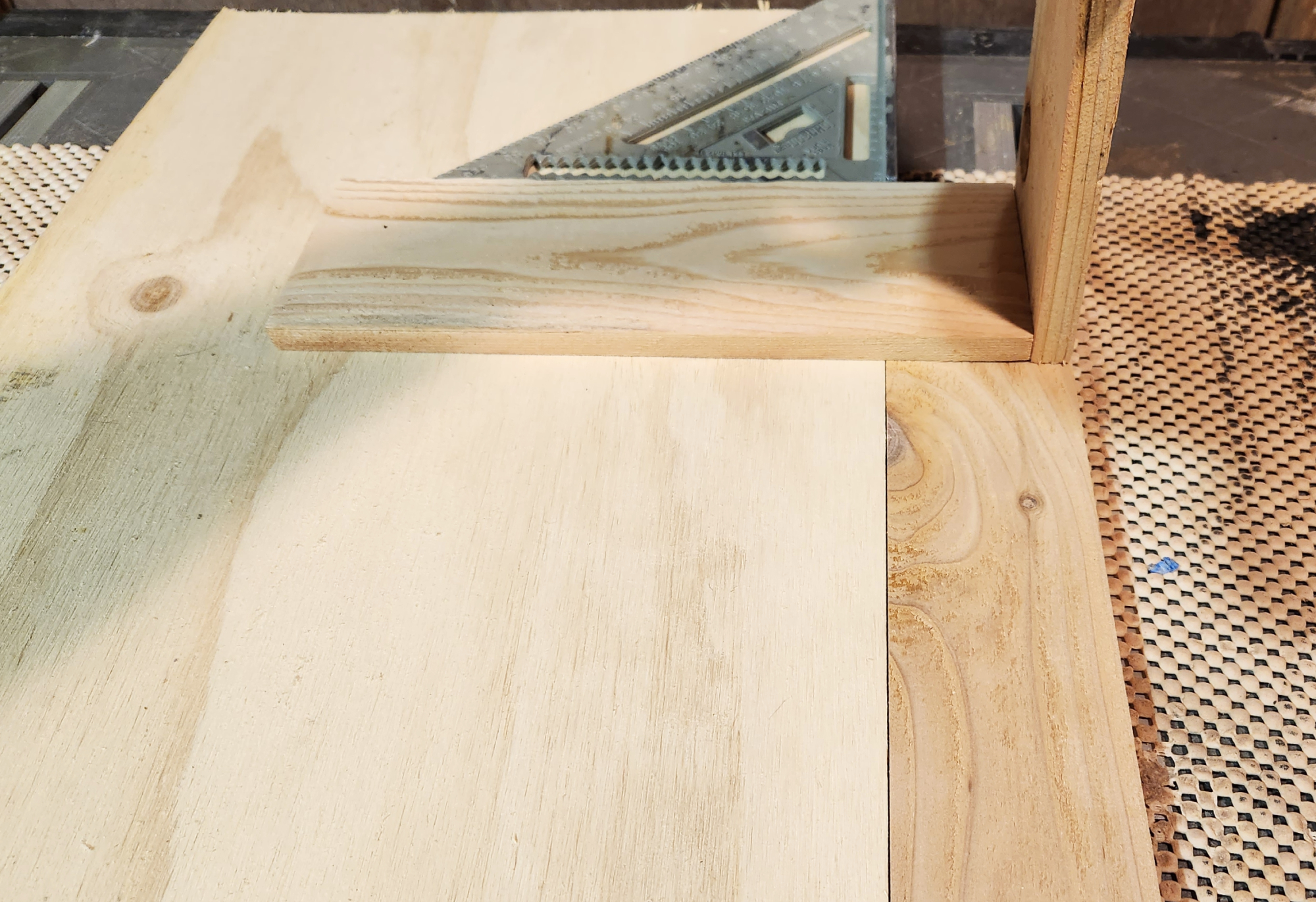 A piece of plywood used as a jig to align pieces of cedar for the side panel of a DIY planter box.