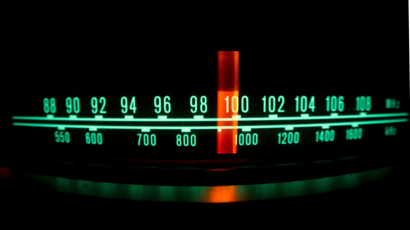 Backlit radio dial showing the marker running through different stations and frequencies