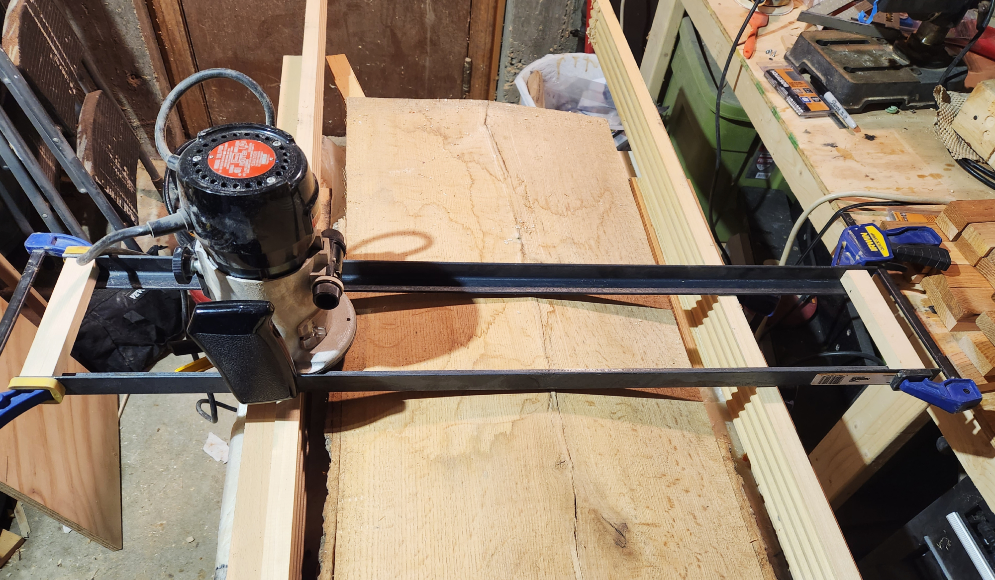 A DIY router sled in position above a warped board in a woodshop.