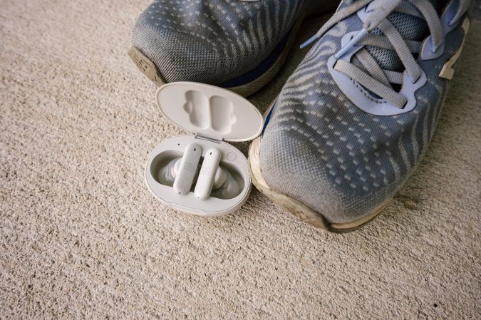  A pair of the Ultimate Ears Fits headphones on some concrete near some sneakers.