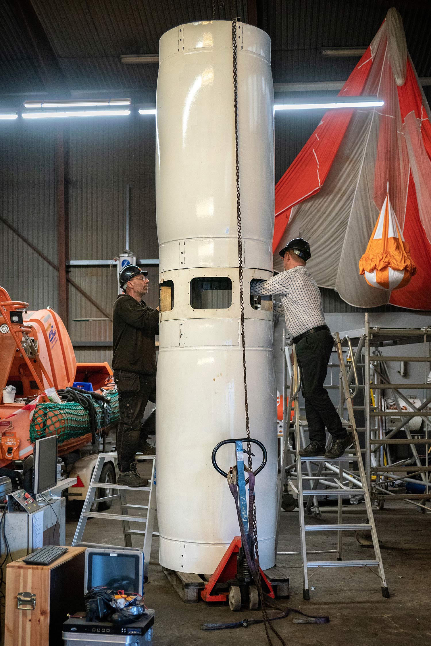 two workers on ladders reach into rocket part