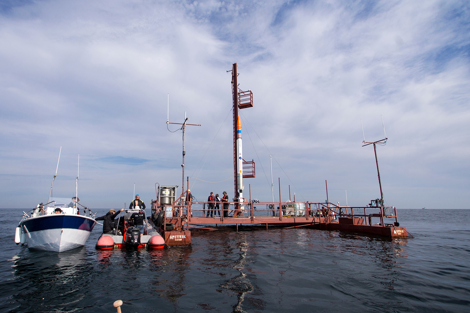 rocket on water-borne platform with boats and people