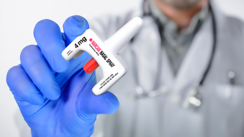 A medical professional holds a nasal spray version of naloxone, an opioid overdose reversal drug.