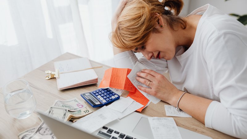 Person crying over bills and a calculator on a desk.