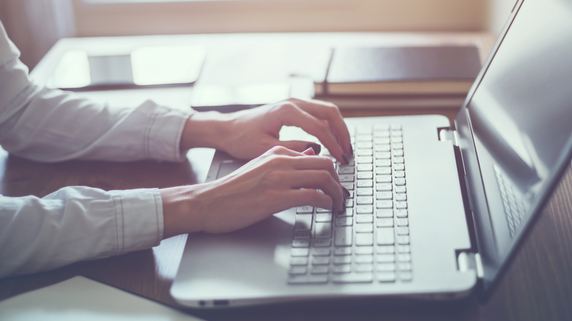 Woman's hands typing on laptop keyboard