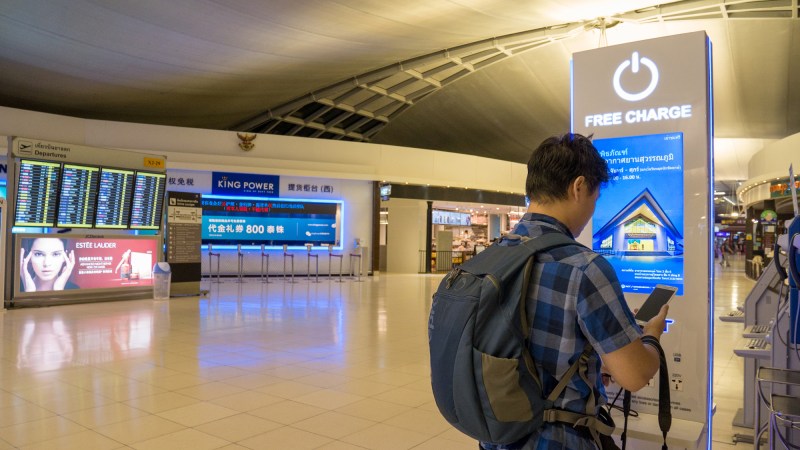 person charging phone at airport charging station.