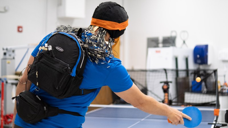 Ping Pong player wearing electrode cap playing against robot ball server