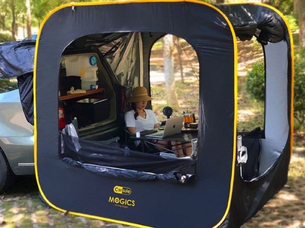 A woman sits in a pop-up cabin tent.