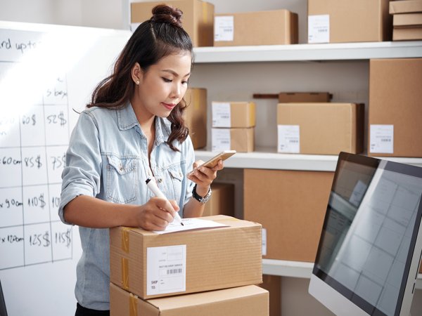 A person writes on a box in a package fulfillment center