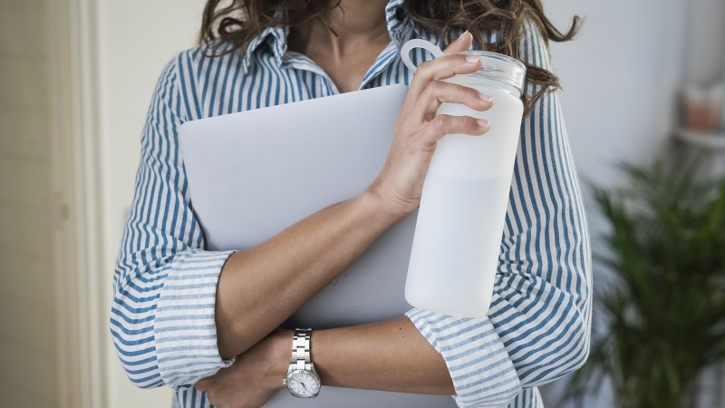 Person holding laptop and a white reusable water bottle.