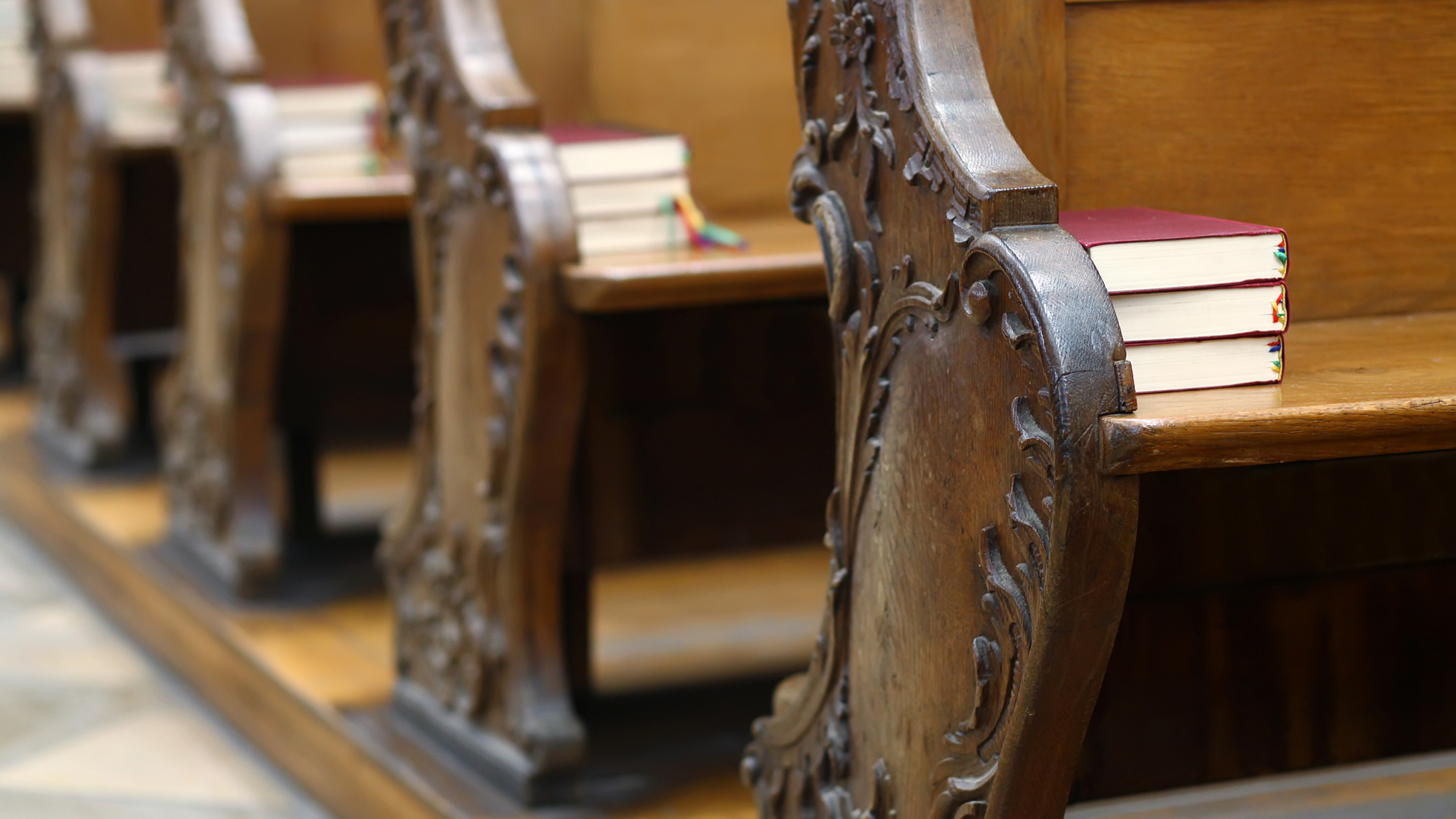 Wooden church pews with prayer books on them