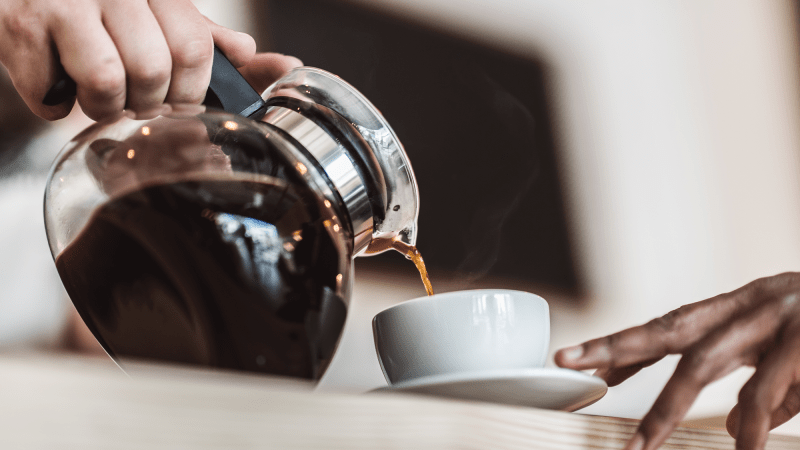 Pouring a cup of hot coffee into a mug.