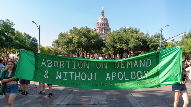 Abortion rights demonstrators march behind a sign that reads "Abortion on demand and without apology," near the State Capitol in Austin, Texas on June 25, 2022. Abortion rights defenders fanned out across America on June 25 for a second day of protest against the Supreme Court's thunderbolt ruling, as state after conservative state moved swiftly to ban the procedure.