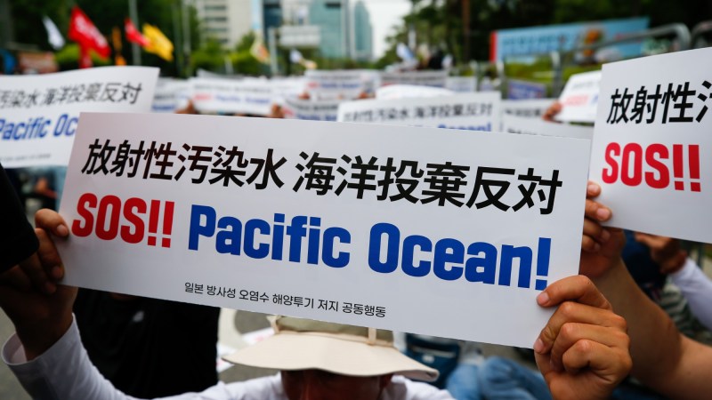 Person holds "SOS!! Pacific Ocean!" sign at Fukushima water release protest.