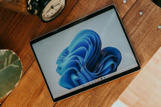 A Windows 11 Pro tablet sitting on a wooden table.