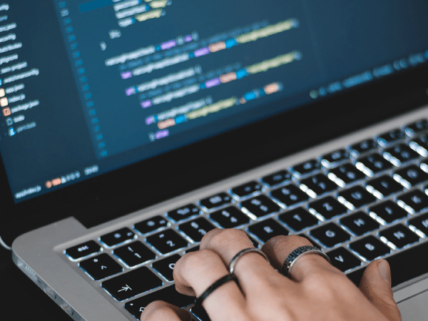 A person wearing rings coding on a MacBook Pro