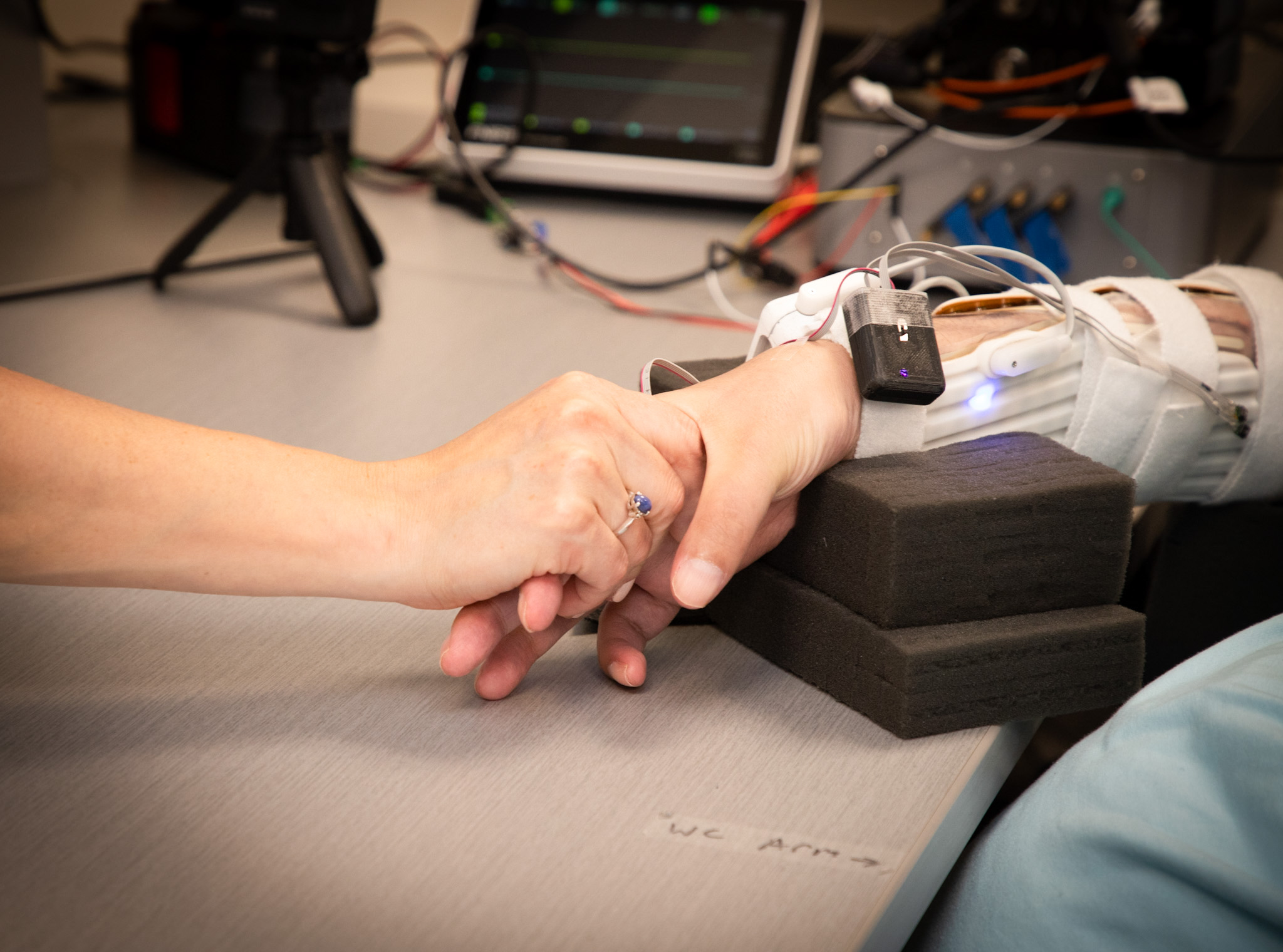 Paralyzed man's hand holding his sister's hand after neurosurgery implant.