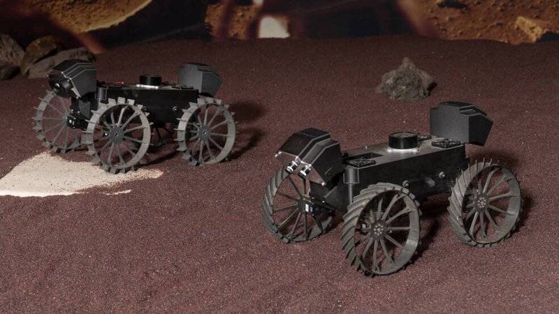 Two NASA lunar CADRE rovers parked on the ground