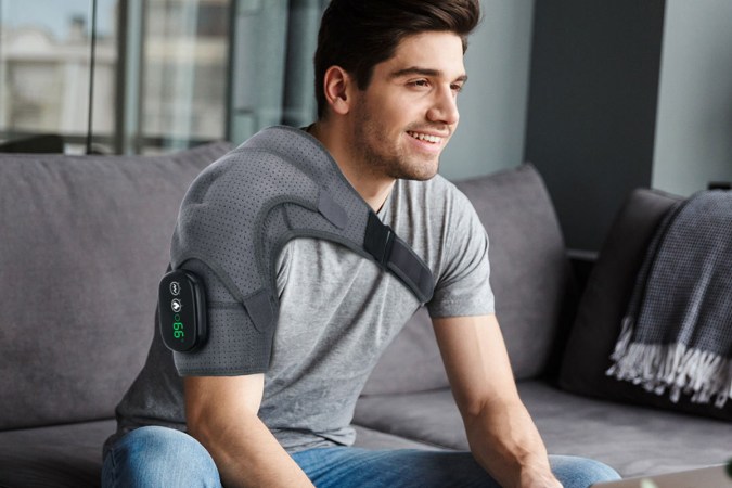 A person wearing a massage belt on their shoulder.