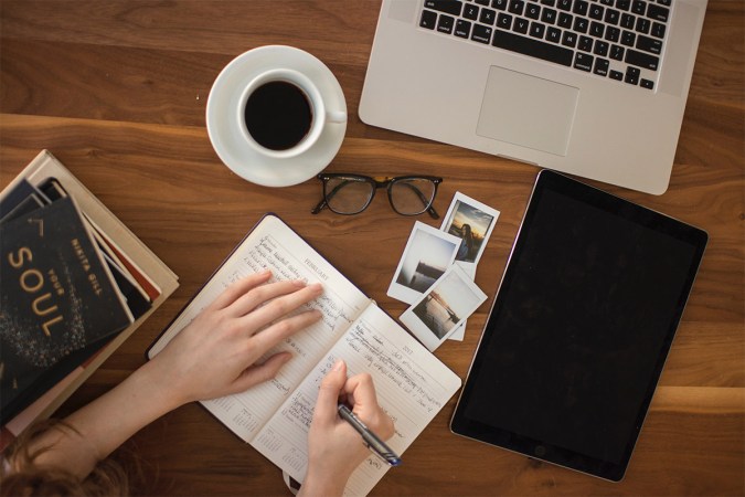 A person writing in a notebook at a desk