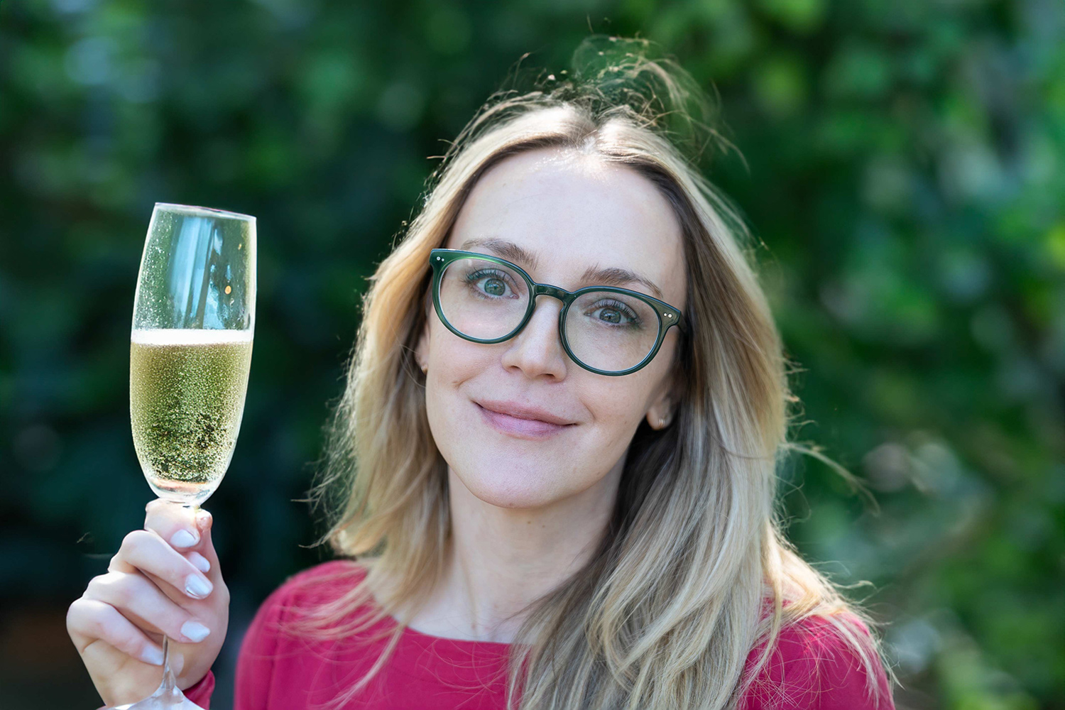 Annie Colbert holding glass of champagne with unnatural-looking hand.