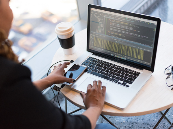 A person coding on a laptop in a cafe