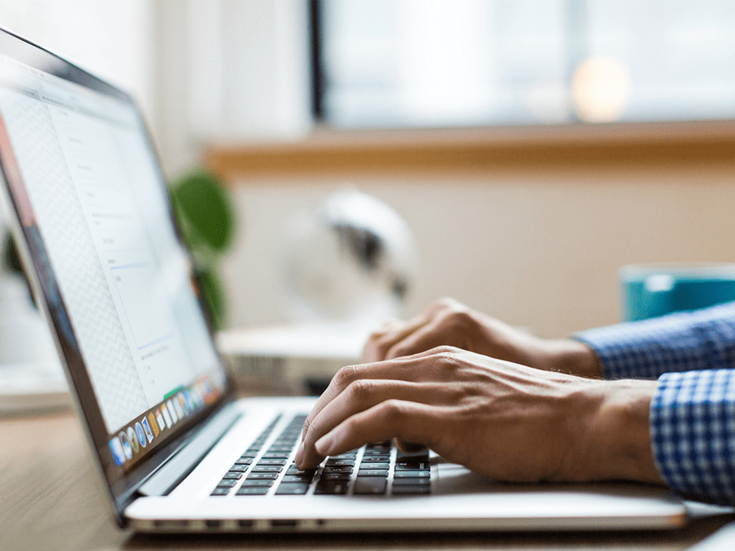 A person typing on a silver laptop